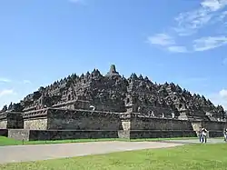 A terraced pyramid like structure with a stupa on top.