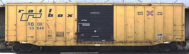 A yellow boxcar with a Railbox logo painted in black