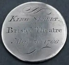 Circular, silver token, engraved with text