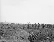 Black and white photo of men in and around WWI trenches.