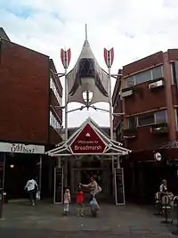 Narrow entrance with glass canopy between high brick buildings