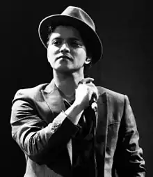 A black and white photograph of Bruno Mars holding a microphone.