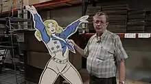 Buddy Saunders (right) in his warehouse with Dallas Cowboy Cheerleader cutout during production of the short documentary "Dallas Marvels" in 2015