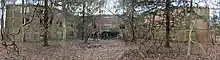 A panoramic image showing a large "H-shaped" building overtaken by nature due to Bainbridge's abandoning.