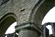 Capital of a column in the north nave, showing scalloped decoration. Above it a putlog hole, used for supporting scaffolding during construction.