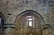 Arch on north side of nave with scalloped capital and a view through the building to the clerestory on the south side.