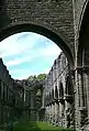 A view of the west windows and the nave seen from the church crossing, looking under a corbel arch supporting the central tower.