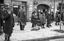 People walking on a paved surface around a still body