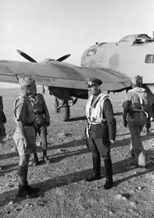 four men in military uniforms standing in front of a propeller-driven aircraft