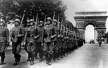 Soldiers walking down Champs-Élysées, with Arc de Triomphe in the back