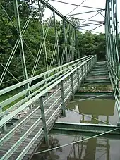 An image of the wooden walkway spanning the length of the green Whipple truss bridge