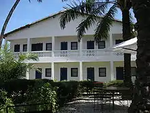 A white, two-story building surrounded by trees