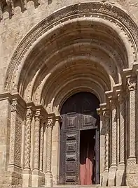 Detail of the main door with its intricate carved columns and arches and a corbel row separating the front window.