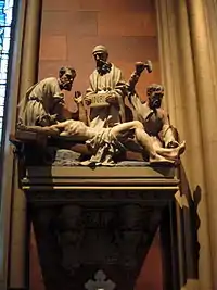 Small stone statuary, mounted on a wall, depicting the crucifixion of Jesus