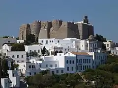 Monastery in dark stone, white houses below