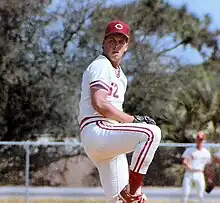 A man in a white baseball uniform and red cap