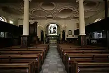 Church interior with wooden pews, decorated ceiling, and large columns