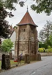 Colour photograph of the tower and railings with tree branches obscuring the view in the foreground.