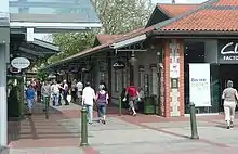 Paved shopping street with shops on either side. Green bollards