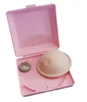 A diaphragm contraceptive device, shown with its box, and a coin (it is about 3 times wider than the quarter).