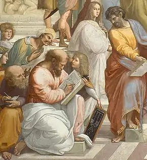 Scene from Raphael's School of Athens showing Pythagoras as a balding, bearded man writing in a book with a quill. He is dressed in a long-sleeved tunic with a cloak spread across his legs as he kneels to write, using his left thigh to support the book. In front of him, a boy with long hair presents him with a chalk board showing a diagrammatic representation of a lyre above the symbol of the tetractys. Averroes, shown as a stereotypical Middle Easterner with a mustache and wearing a turban, peers over his left shoulder while another bearded, balding philosopher in classical garb, probably Anaxagoras, peers over his right shoulder, taking notes into a much smaller notepad. A very feminine looking figure with long hair stands behind the boy, dressed in a white cloak.