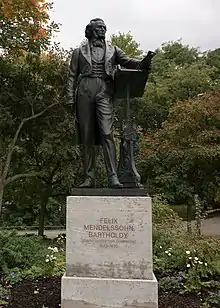 Bronze statue of a formally dresded man standing near a lecturn