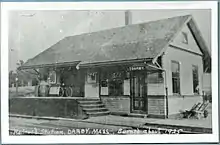 A black-and-white postcard of a small wooden railway station