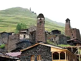 Stone houses with several towers, hill in the background