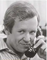 A young man holding a telephone.