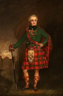 Elderly man in Highland dress with a green coat and various medals, wearing spectacles (eyeglasses) and leaning on a basket-hilted sword