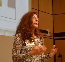 This image shows Dene Grigar speaking in an auditorium at the University of Victoria, British Columbia.