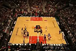 An indoor arena filled with people watching a basketball game.