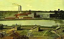 Postcard showing housing in the foreground, a body of water, and Cone Mills buildings in the background