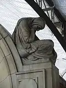 The crouching figure at top right of the memorial wall.