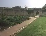 a path leading to an archway through a stone wall