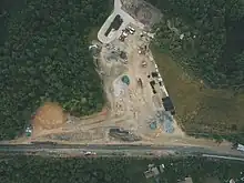 Aerial view of a construction site next to a rail line in a wooded area