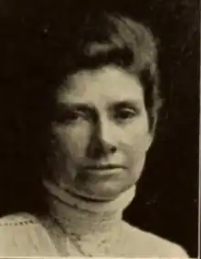 A white woman wearing a high-collared white blouse or dress; her dark hair is in a bouffant updo