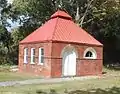 The small utility building at the William Enston Home in Charleston, South Carolina is built of dark red brick.