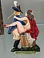 French painted metal figurine, c 1900, showing a Chevalier seducing his mistress on a campaign drum