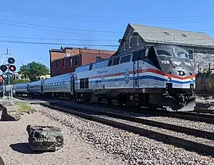 A passenger train with a diesel locomotive at a grade crossing