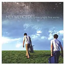 Two people walking across a grassy patch of land with the cloudy sky taking up most of the view