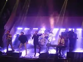 FFS performing in 2015 at the Albert Hall in Manchester. From left to right: McCarthy, Russell Mael, Kapranos, Ron Mael (foreground), Thomson, Hardy (background).