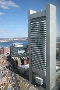 Aerial view of a tall, narrow, concrete skyscraper; the building's design somewhat resembles that of a washboard, with uninterrupted horizontal rows of windows protruding slightly outward from two of the building's four sides