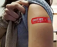 A young woman displays her bandage after receiving the vaccine at a drug store