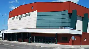 Exterior of arena featuring bricks painted in white, and red and blue trim around the doors and roof