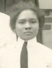 A young Black woman wearing a white collared shirt and a necktie