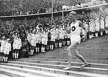 Athlete running down steps holding the Olympic torch