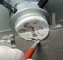 Advancing the specimen over the blade while holding the section down to prevent it from folding onto itself