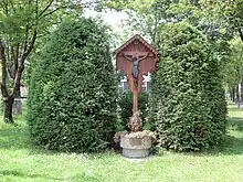 A memorial stone erected next to a road curb. Nearby is a metal pole topped by a written sign.