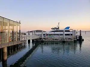 A ferry at a dock in a large harbor